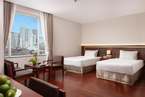a hotel room with two beds and a large window at Phnom Penh Katari Hotel in Phnom Penh