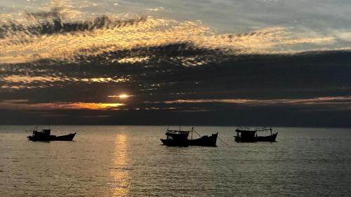 three boats sitting in the water at sunset at TS Beach House in Phu Quoc