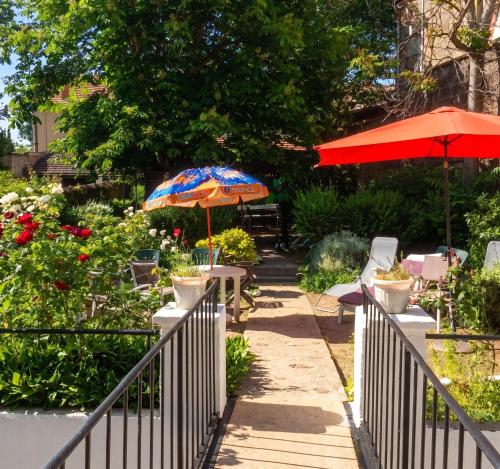 a patio with tables and umbrellas in a garden at Charmant studio à Néris-les-Bains 20 m² avec jardin privé in Néris-les-Bains
