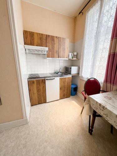 a small kitchen with wooden cabinets and a table at Charmant studio à Néris-les-Bains 20 m² avec jardin privé in Néris-les-Bains