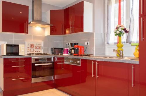 a kitchen with red cabinets and stainless steel appliances at Appartement spacieux Gérardmer 90 m² in Gérardmer