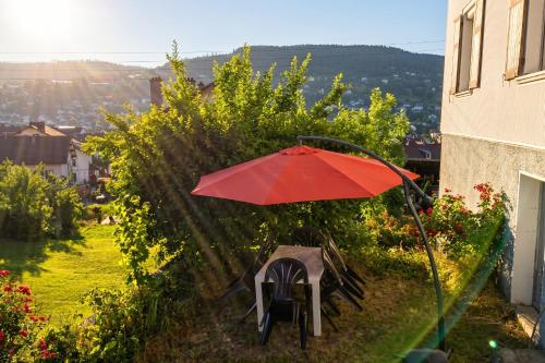 a red umbrella and chairs sitting in a garden at Appartement spacieux Gérardmer 90 m² in Gérardmer