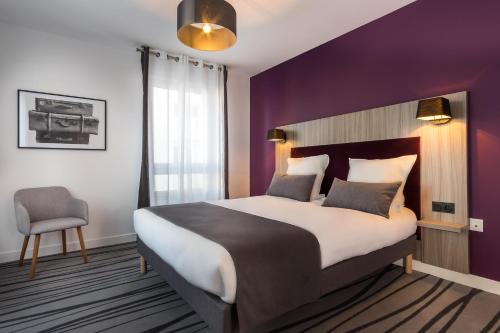 una camera con un grande letto e una parete viola di Nemea Appart Hotel Quai Victor Tours Centre a Tours