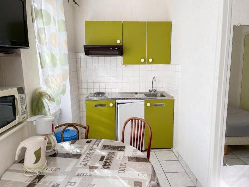 a small kitchen with green cabinets and a table at Charmant studio à Néris-les-Bains de 20 m² in Néris-les-Bains