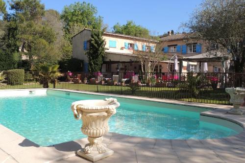 a pool with a statue in front of a house at Logis La Bastide des Golfs in Mouans-Sartoux