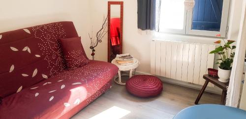 a living room with a red couch and a window at Studio cosy à Camembert - 20 m² avec terrasse et parking in Camembert