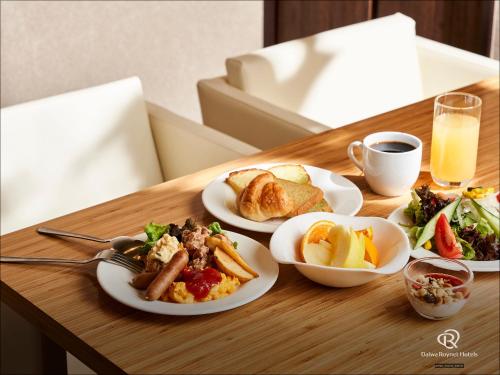 a wooden table with plates of food on it at Daiwa Roynet Hotel Tsukuba in Tsukuba
