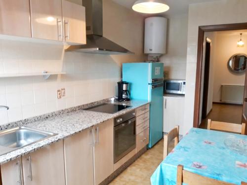 a kitchen with a blue refrigerator and a table at Welcoming Apartment in A Coruña, 90 m², Balcony in Serres