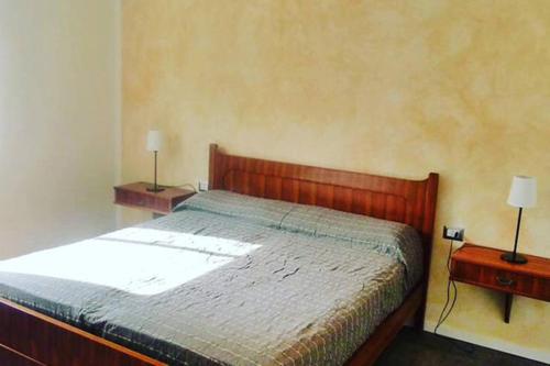 a bedroom with a bed with two nightstands and two lamps at Apartment Piccolo Borgo in Castelveccana