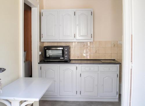 a kitchen with white cabinets and a microwave at Appartement charmant à Plancher-les-Mines 40 m² avec jardin in Plancher-les-Mines