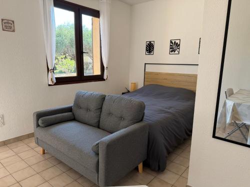 a bedroom with a couch and a bed and a window at Studio cosy tout confort proche ARKEMA in Château-Arnoux-Saint-Auban