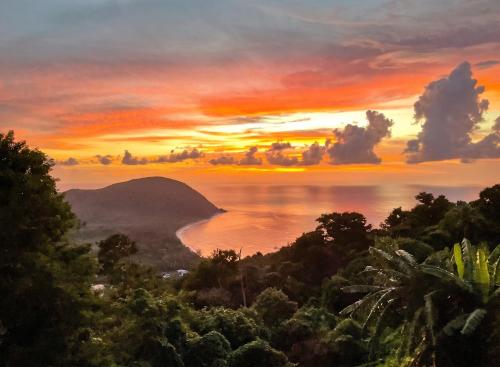 a painting of a sunset over a body of water at Appartement confortable à Deshaies avec vue sur la mer - 55 m² in Deshaies