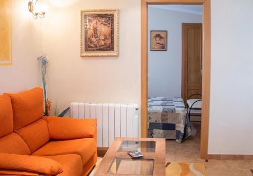 a living room with an orange couch and a table at Charming Villa with Private Pool in La Calzada de Béjar in La Calzada de Béjar