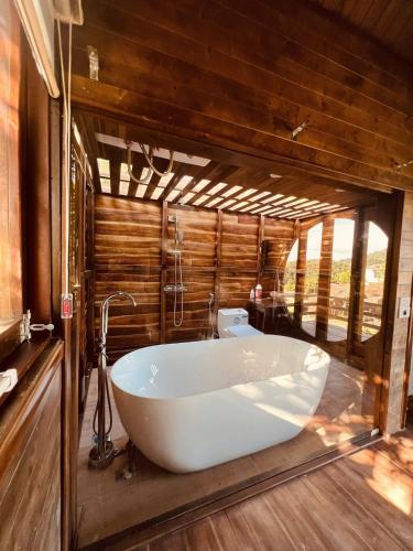 a white bath tub in a bathroom with wooden walls at Sunny Camping Sóc Sơn in Sóc Sơn