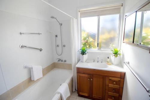 a white bathroom with a tub and a sink at Manilla Cottage - Manilla NSW in Manilla