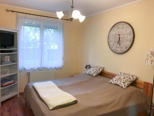a bedroom with a bed with a clock on the wall at Lily House in Balatonvilágos