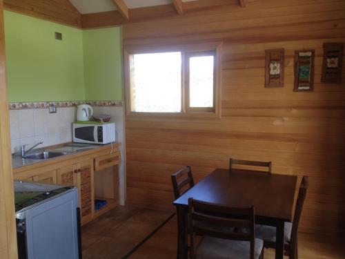 a small kitchen with a table and a microwave at Cabañas Torre Huillinco in Huillinco