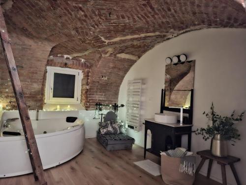 a bathroom with a white tub and a brick wall at Villa Lu alloggio con idromassaggio e piscina in Carignano
