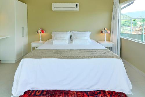 a bedroom with a large white bed with two lamps at Louise village in Juquei