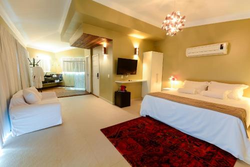a bedroom with a large bed and a living room at Louise village in Juquei