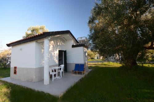 a small white building with two chairs in a yard at Villaggio Turistico Elea in Ascea