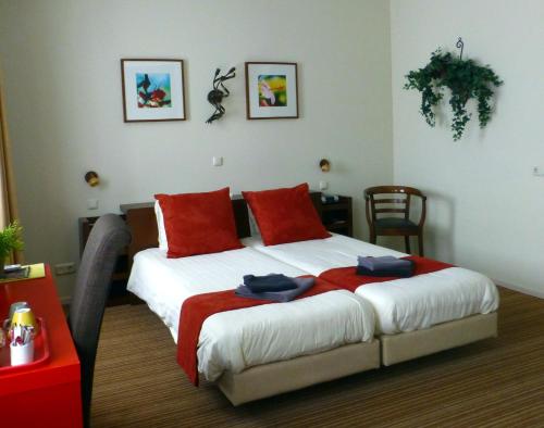 ein Schlafzimmer mit einem großen Bett mit roten Kissen in der Unterkunft Hotel Restaurant Het Roode Hert in Dalfsen