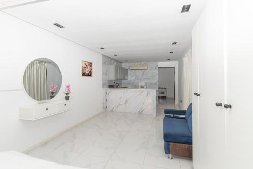 a white living room with a mirror and a blue chair at Jeddah Apartment in Jeddah