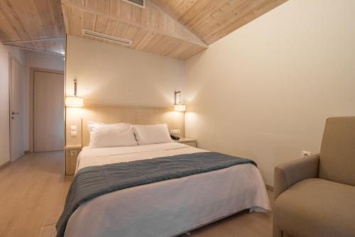 a bedroom with a large bed and a chair at Cosmopolitan Hotel in Paralia Katerinis