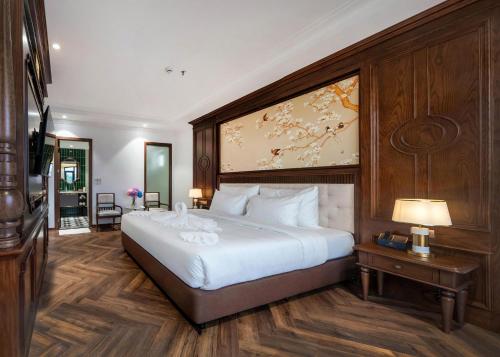 a bedroom with a large white bed with a wooden headboard at Diamond Hotel Yen Bai in Yên Bái