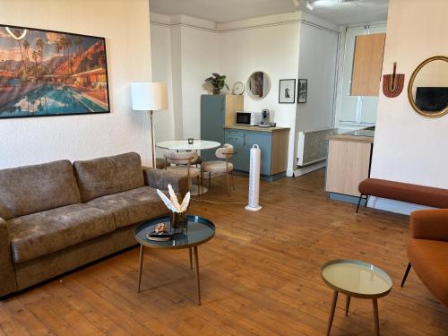 a living room with a couch and tables and a kitchen at Le Grand Briand - Champ de Mars in Valence