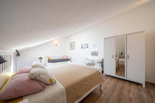 a white bedroom with a large bed and a desk at Apartments TERRAeSAL in Zadar