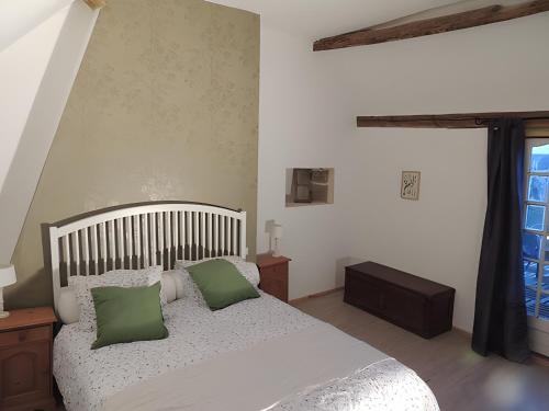 a bedroom with a bed with two green pillows at Gite Grand-Mère in Charron