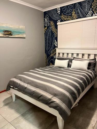 a bedroom with a large bed with a striped blanket at Flamingo Park D1 Langebaan in Langebaan