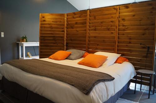 Un dormitorio con una cama grande con almohadas naranjas. en Gîte La Malonière, en Saint-Martin-du-Bois