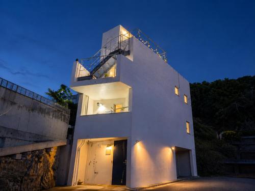 a white building with a balcony on top of it at Balmy Ocean OKINAWA in Yomitan