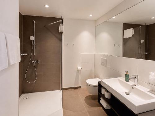 ein Badezimmer mit Dusche, Toilette und Waschbecken in der Unterkunft in2 The Hotel in Xanten