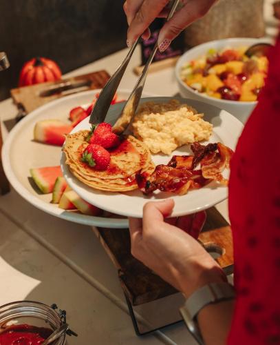 a person holding a plate of pancakes and fruit at Le Riviera - Hôtel Restaurant & Spa - Ex Golden Tulip Aix les bains in Aix-les-Bains