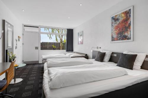 a row of white beds in a room at Hotel Hedegaarden in Vejle