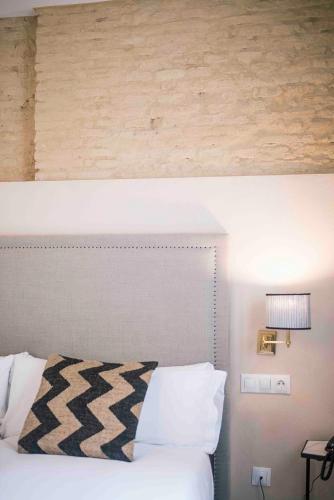 a bedroom with a white bed and a lamp at Casa Boutique La Pila del Pato in Seville