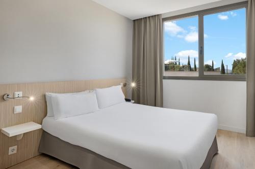 a bedroom with a large white bed and a window at B&B HOTEL Barcelona Sant Cugat in Sant Cugat del Vallès
