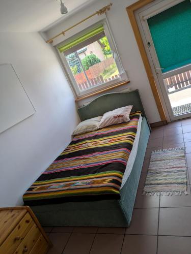 a small bed in a room with a window at Biały domek przy Hajnówce in Dubiny