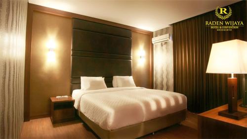 a bedroom with a large bed and a lamp at Raden Wijaya Hotel & Convention in Mojokerto