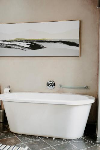 a white bath tub in a bathroom with a picture on the wall at Godiva Spa & Guesthouse in Groblersdal