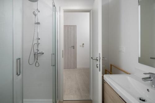 a white bathroom with a shower and a sink at Apartment Complex Vetrina-Shared Pool in Nova Vas