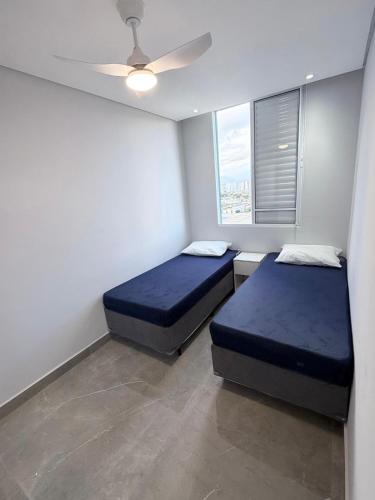 a bedroom with two beds and a ceiling fan at Apartamento 2 quartos na baixada in São Vicente