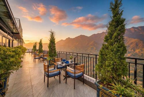 a balcony with tables and chairs and a view of mountains at DeLaMont Sapa Hotel - Hill Serenity Retreat in Sapa