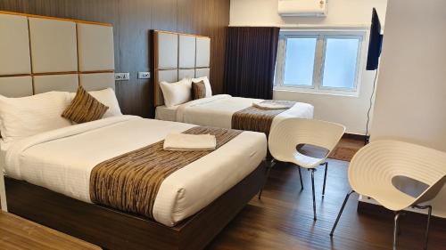 a hotel room with two beds and a table and chairs at Le Grace Bye Pass in Madurai