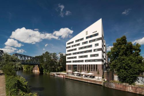 a white building next to a river with a bridge at INNSiDE by Meliá Hamburg Hafen in Hamburg