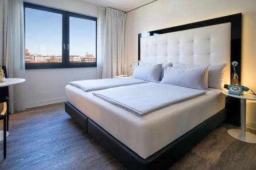 a large white bed in a room with a window at INNSiDE by Meliá Hamburg Hafen in Hamburg