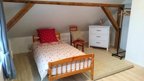 a bedroom with a wooden bed with a red pillow at Gîte de montagne -Bellefosse Alsace in Bellefosse